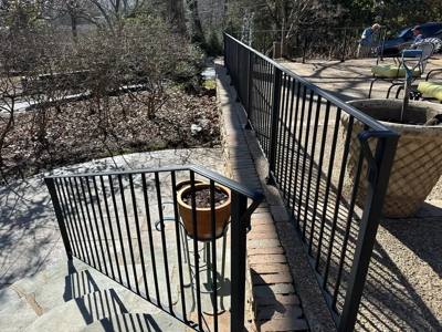 Black picket railings enclosing stone steps and an elevated patio