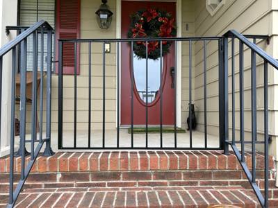 Black picket railings framing brick steps at a red front door