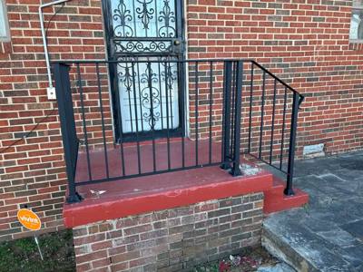 Black picket rails at a red-painted entry platform and decorative security door
