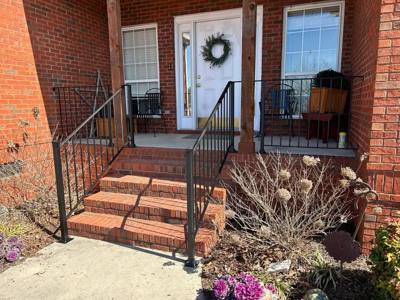 Black picket rails beside brick porch steps and a landscaped bed