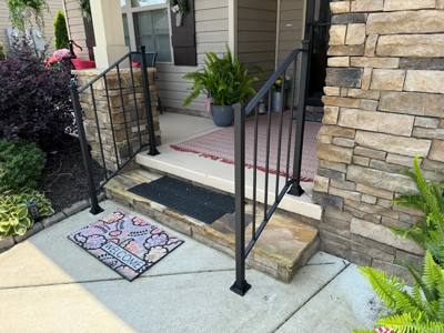 Black picket rails beside short stone-faced porch steps