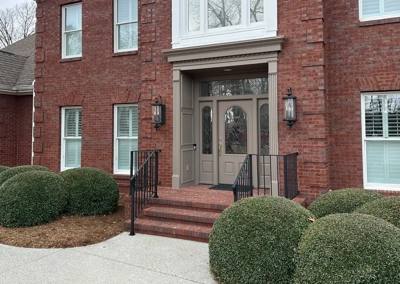 Black picket rails framing brick steps to an arched double-door entrance