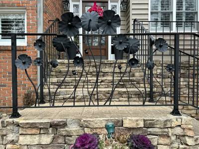 Black porch panel with sculpted flowers and curved stems above a stone wall