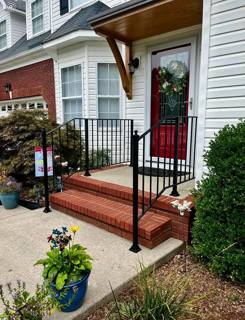 Black porch railings and red entry steps beneath a timber-supported roof
