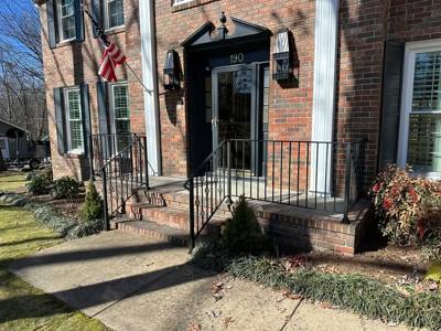 Black porch railings at a brick house with a dark front door