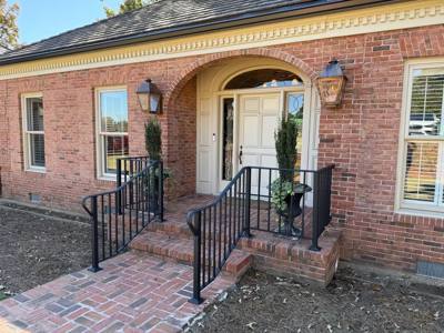 Black porch railings beside an arched brick entrance