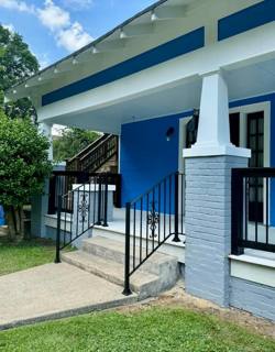 Black porch railings beside concrete steps at a blue-and-white house