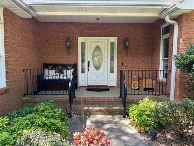 Black porch railings framing brick steps beneath a covered entrance