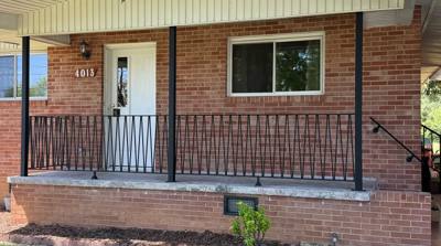 Black railing across a brick front porch and short entry steps