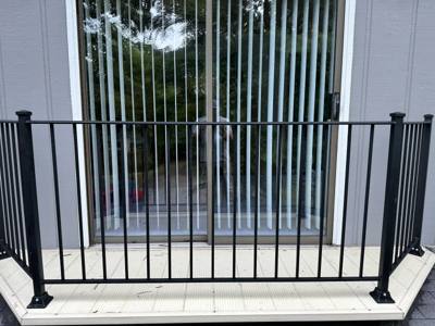 Black railing across a small balcony in front of glass doors
