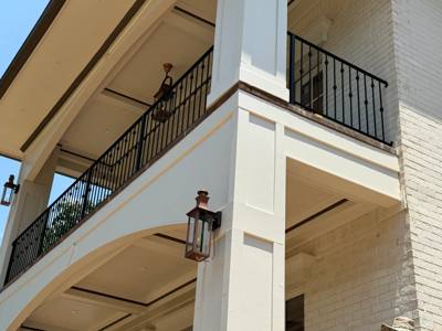 Black railing along an upper covered balcony viewed from below
