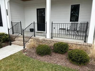 Black railing around a white-columned porch with a central stair opening