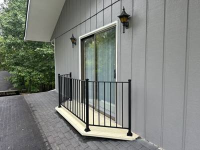 Black railing enclosing a narrow landing outside a sliding glass door