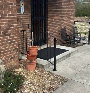 Black railing enclosing a small brick-side entrance landing