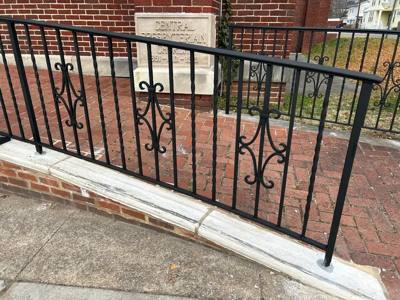 Black railing panels with central scroll accents above brick paving