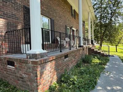 Black railing spanning a long raised brick porch