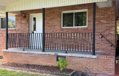 Black railing with diagonal diamond accents across a covered brick porch