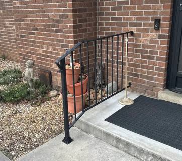 Black railing with twisted decorative pickets beside a concrete doorstep