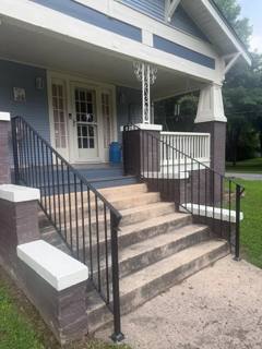 Black railings around a white porch and broad concrete entry steps