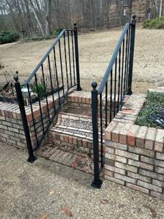 Black railings beside brick steps leading through a low garden wall