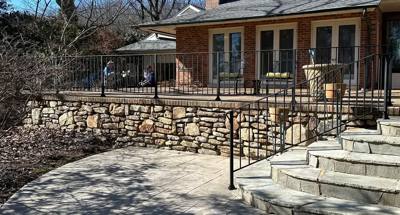Black railings bordering a stone terrace and curved entry steps