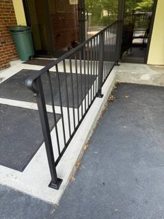 Black railings enclosing an entrance ramp beside a glazed building frontage