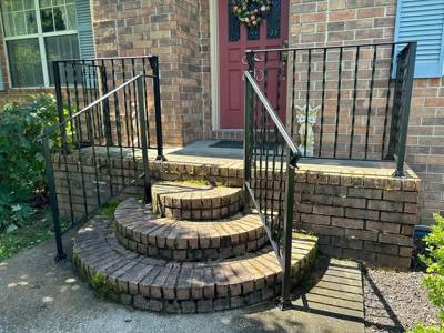 Black railings flanking rounded brick entry steps