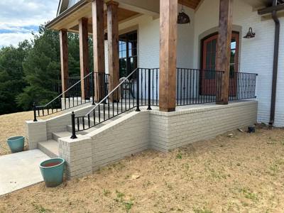 Black railings following pale porch steps beneath large timber columns