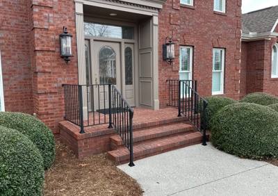 Black railings framing a brick stairway at a recessed double-door entrance