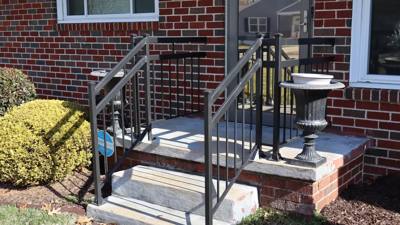Black railings framing a small concrete stoop beside a brick house