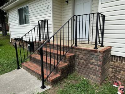 Black railings framing brick steps at a white-sided entrance