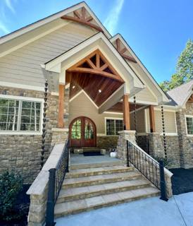Black railings framing broad stone entrance steps beneath a timber porch gable