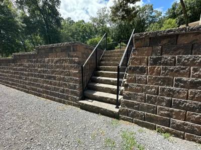 Black railings on a stone stairway through a tall retaining wall