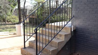 Black railings on concrete side steps beside a dark brick wall