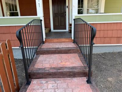 Black railings with curved ends beside pink-toned porch steps
