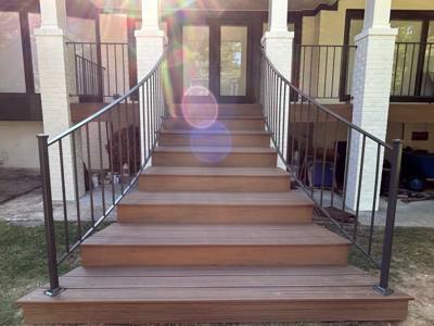 Black railings with curved ends flanking broad wooden porch steps