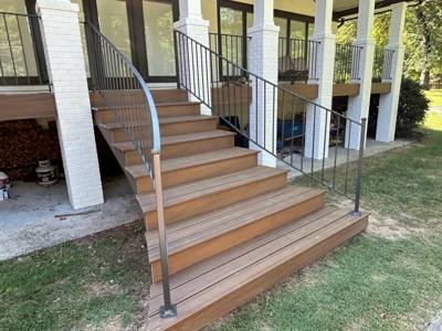 Black railings with flared handrail ends beside wooden porch steps