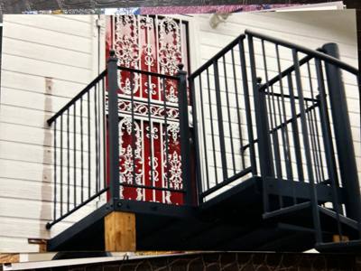 Black raised entry landing with picket railings and a patterned security door
