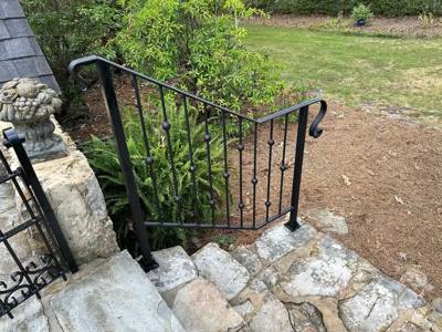 Black scroll-accent handrail beside stone garden steps