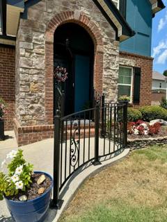 Black scroll-accent railings beside an arched brick doorway