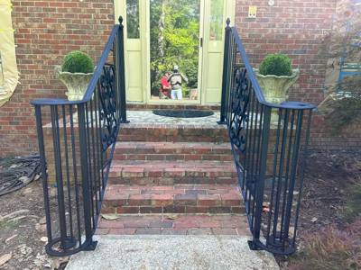 Black scroll-accent railings framing brick steps between large planters