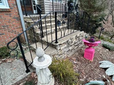 Black scroll-end railings around stone porch steps and a curved landing