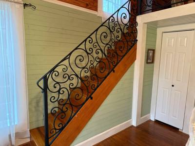 Black scrolling balustrade beside a wooden interior staircase
