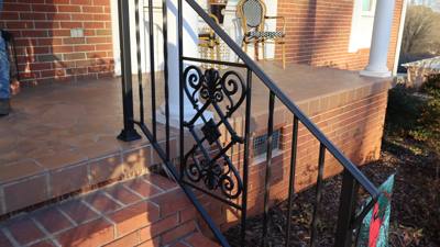 Black scrollwork railing panel at the edge of brick porch steps