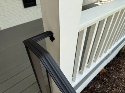 Black shaped handrail returning toward a white porch column