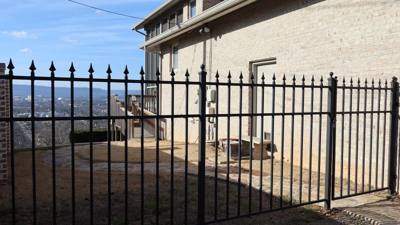 Black spear-top fence and gate enclosing a paved side yard