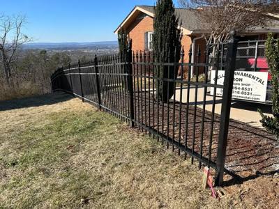 Black spear-top fence enclosing a paved area beside a brick building