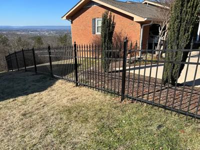 Black spear-top fence following a lawn beside a brick home