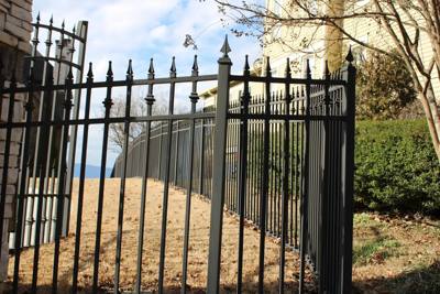 Black spear-top fence with tall posts beside a light-colored building