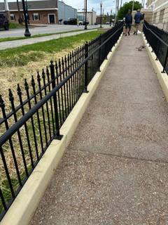 Black spear-top fencing along a long outdoor access ramp beside a street